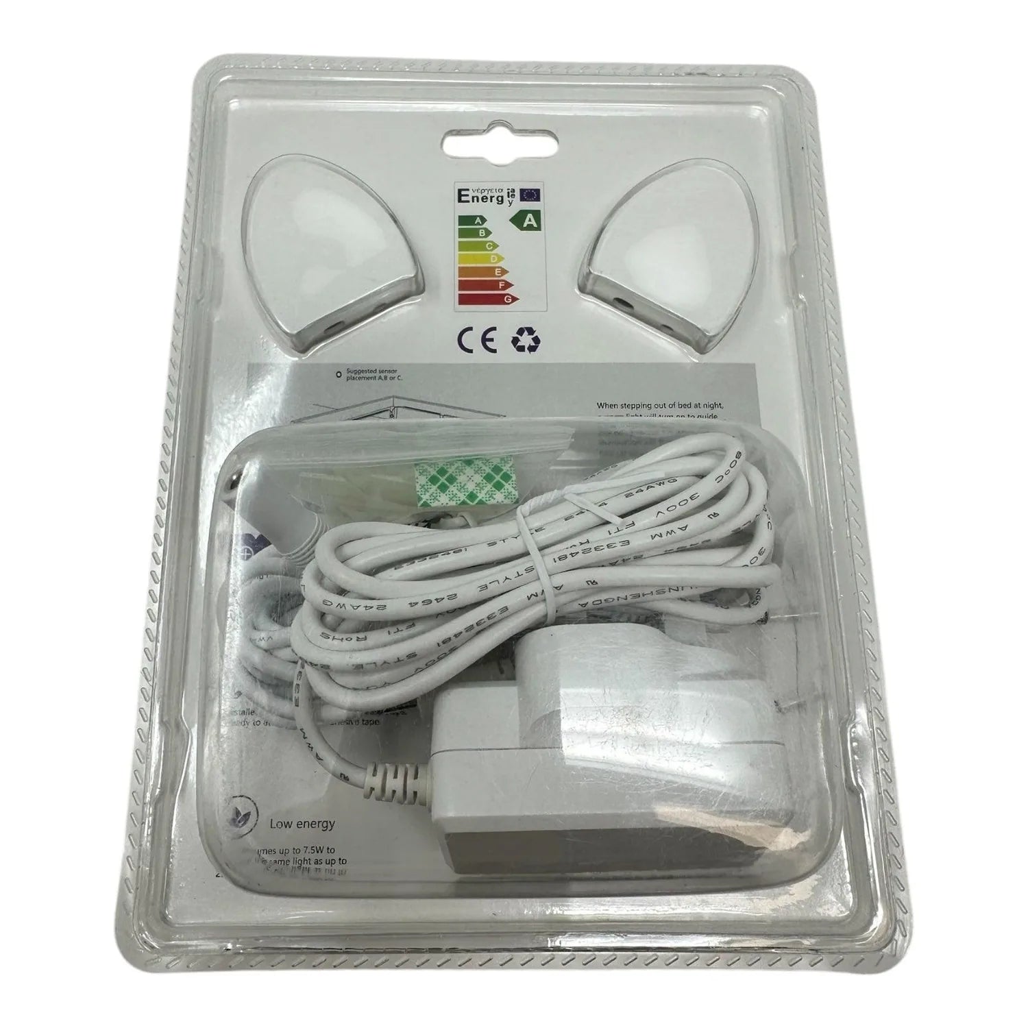 Packaged LED motion sensor light kit showing two white sensor heads, coiled white cord, power adapter, and energy rating labe