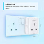 Tapo smart plug installed in UK wall outlet next to traditional switch, showing compact dimensions of 2.03 inches wide by 2.8