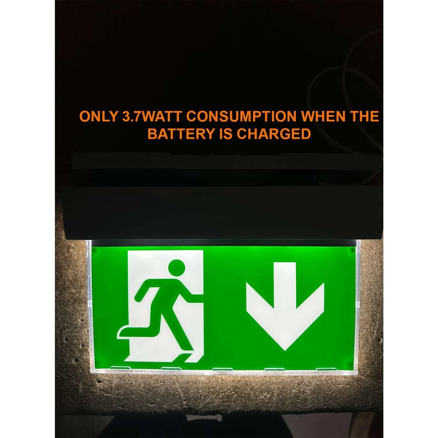 LED emergency exit sign with green background, running figure and downward arrow, mounted on concrete wall. Text states 3.7 w