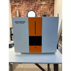 Voltagon Energy Systems hybrid inverter charger with blue side panels and orange center section, displayed on white table aga