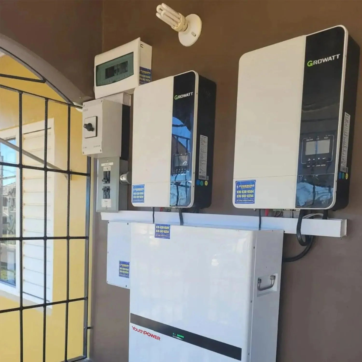 Growatt and YouthPower inverter system installed on brown wall with white mounting bracket and monitoring equipment above yel