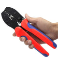 Hand holding red and blue handled MC4 crimping tool with black head against white background.