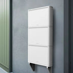 White stackable battery storage units mounted vertically on gray wall with metal mounting brackets, installation shot.