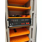 Pylon Tech US5000 battery enclosure mounted in white server rack with orange shelving and cables stored above.