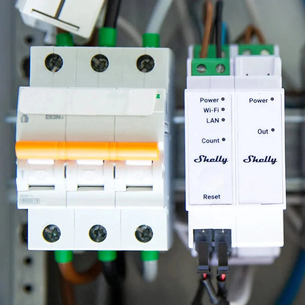 Two Shelly smart relays mounted on DIN rail next to circuit breaker, showing power and connectivity indicators.
