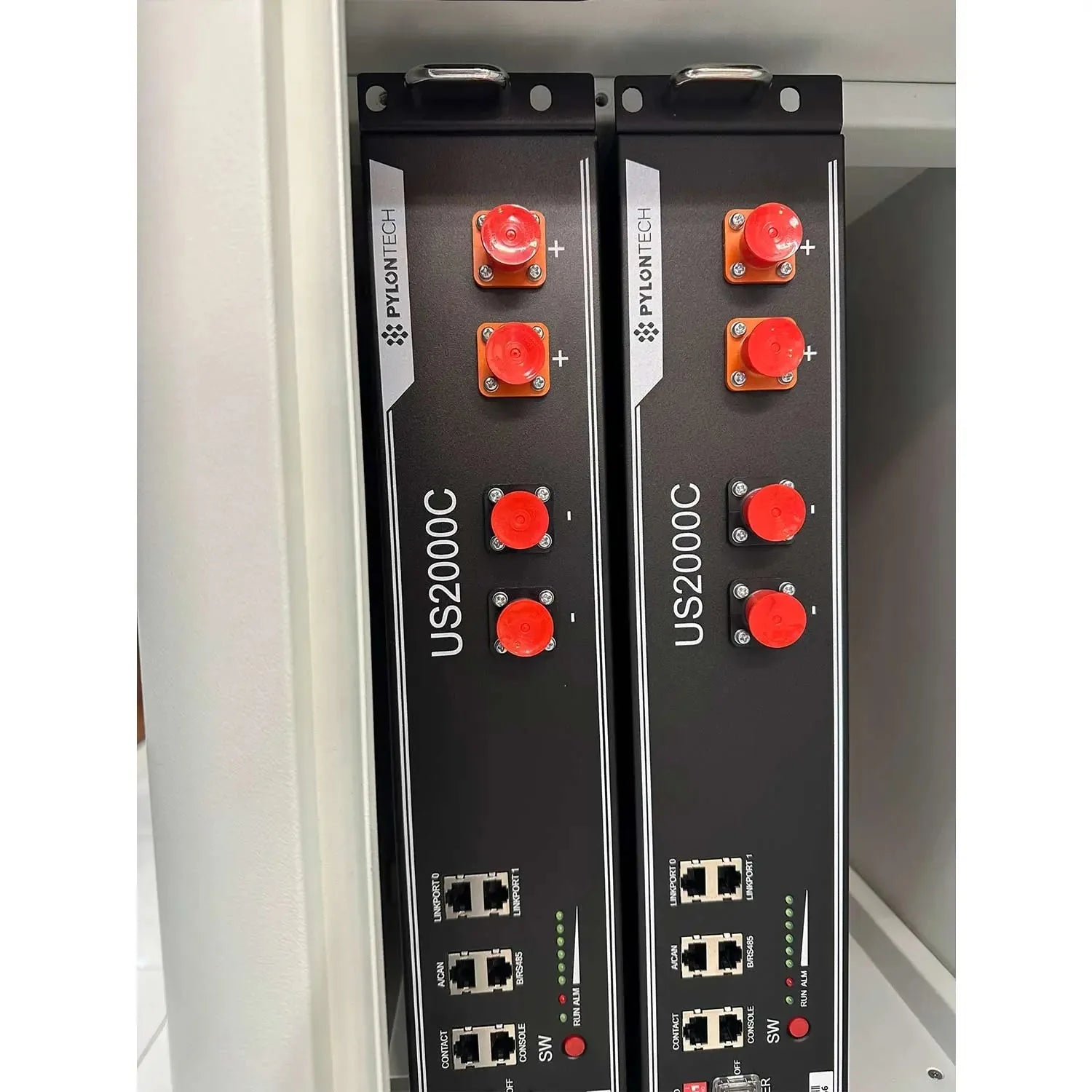 Two black Pylontech US2000C lithium battery cabinets mounted vertically, each with red connectors and network ports, shown in