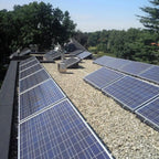Solar panel mounting trays installed on a flat roof with gravel ballast, multiple panels angled at 15 degrees, residential se