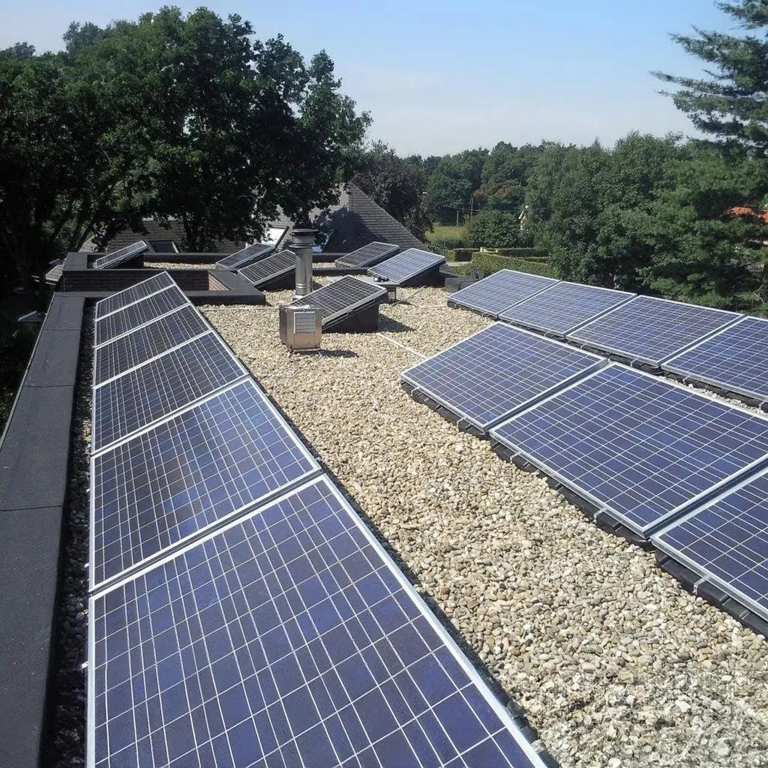 Solar panel mounting trays installed on a flat roof with gravel ballast, multiple panels angled at 15 degrees, residential se