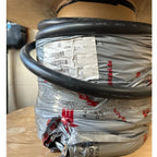 Coiled black electrical power cable with product label and shipping documentation attached, stacked packaging visible below.