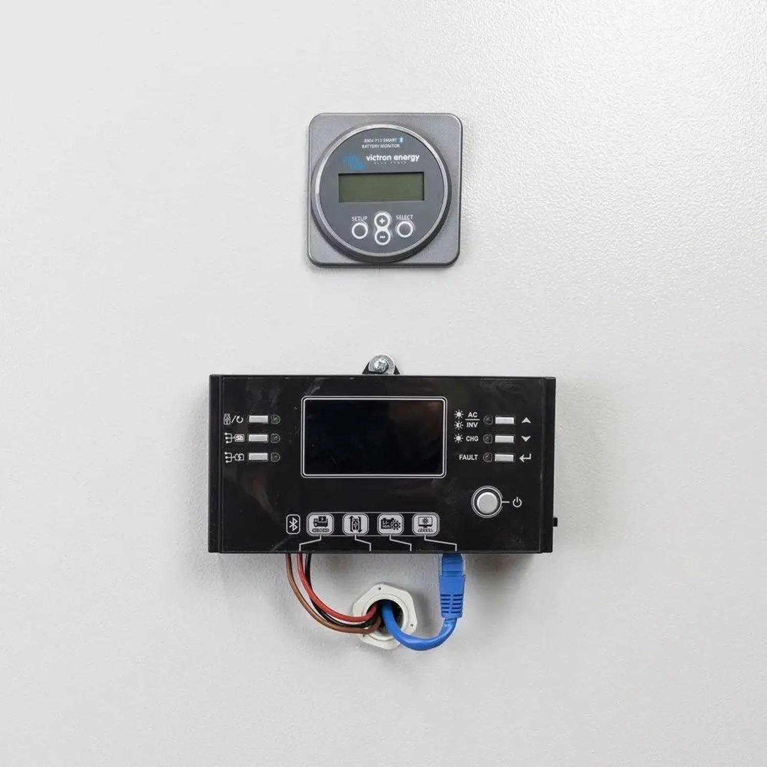 Victron Energy battery monitor mounted above black inverter charger cabinet with digital display, control buttons, and blue p