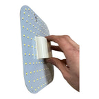 Hand holding a curved LED panel with multiple yellow-white diodes mounted on blue circuit board, showing installation shot of