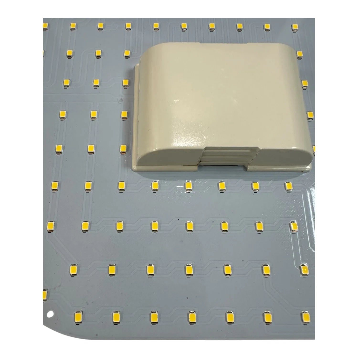 Cream-colored LED 2D lamp positioned on a gray circuit board dotted with yellow surface-mount LEDs, showing the product and i