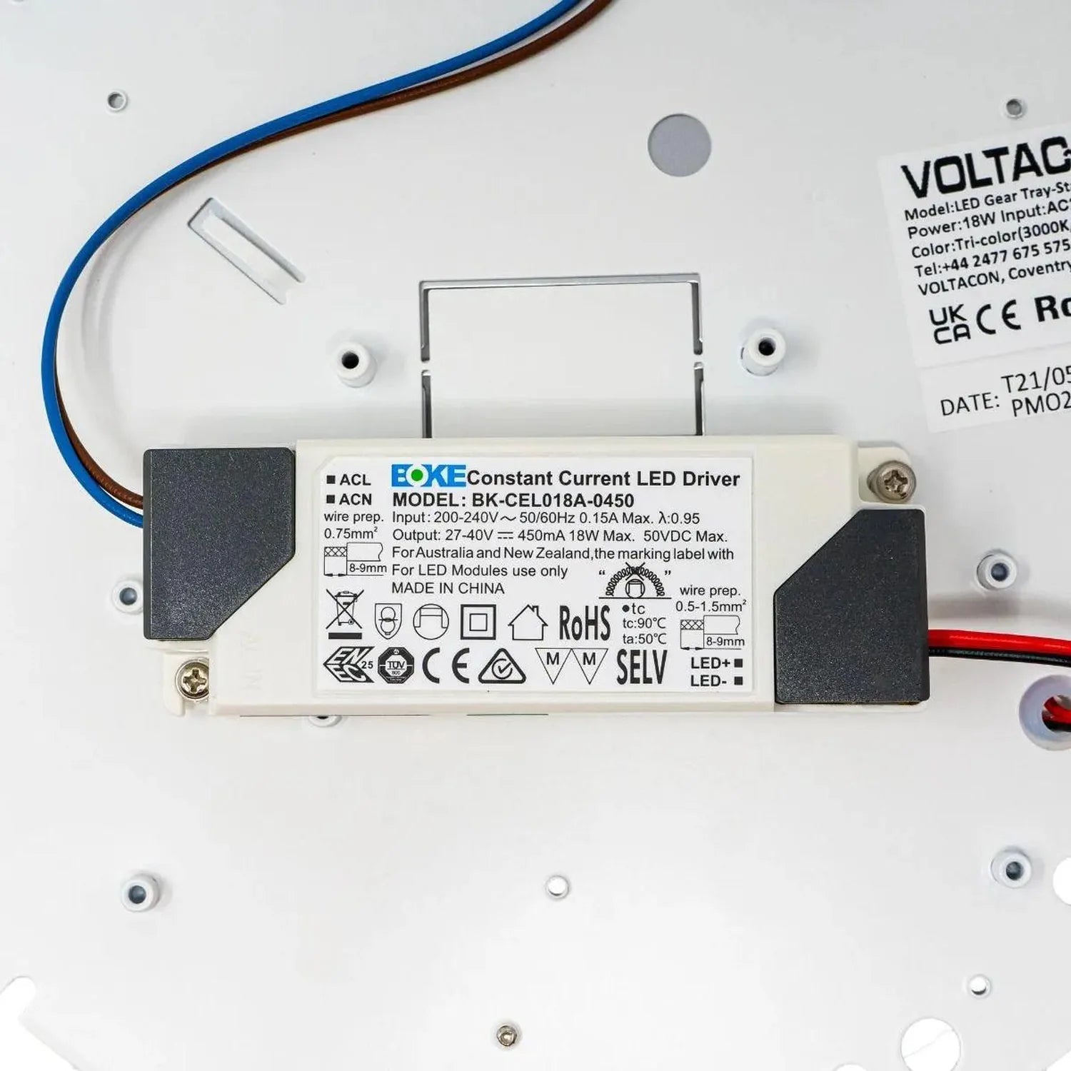 Close-up of LED driver and internal components mounted on white fixture base with blue wiring visible.