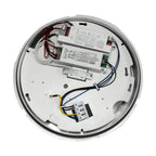 Interior view of round LED retrofit module showing driver components, wiring, and microwave motion sensor mounted on white ba