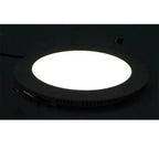 Round LED panel light with bright white center, recessed into black ceiling trim, installation shot.