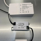 Two white LED driver modules with cables displayed on gray surface, showing specifications and certification labels.