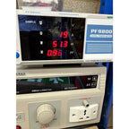 PF9800 digital power meter displaying voltage, current, watts, and power factor readings during testing.