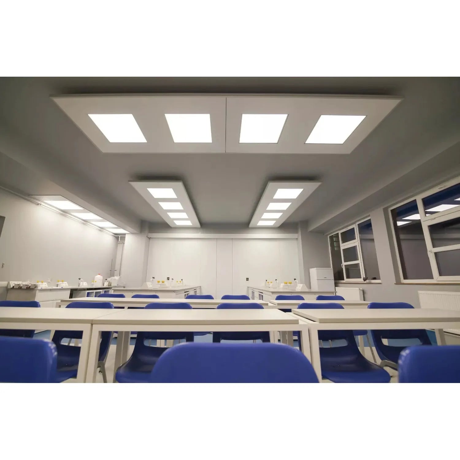 Recessed LED panel lights installed in modern classroom ceiling with blue chairs visible below