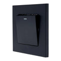 Black 1-gang 2-way light switch mounted on dark wall plate, showing small indicator light above toggle switch.
