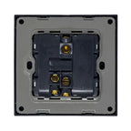 Rear view of black light switch showing internal wiring terminals with brass contact points mounted on gray backing plate.