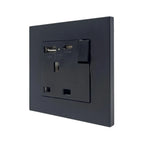 Black wall-mounted electrical socket outlet with USB ports and switch, shown installed against white background.