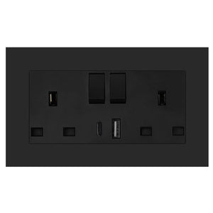 Black dual socket outlet with USB ports mounted on dark wall, showing two power sockets, USB-A and USB-C charging ports, and 