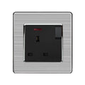 Brushed stainless steel wall socket with black insert, featuring on-off switch and red indicator light, mounted on gray textu