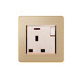 Brushed gold electrical outlet with single switched socket, cream-colored insert, and brown trim ring on white background.
