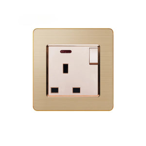 Brushed gold electrical outlet with single switched socket, cream-colored insert, and brown trim ring on white background.