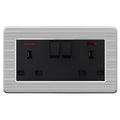 Brushed stainless steel dual outlet socket with two black switches, indicator lights, and USB ports on each side.