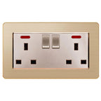 Gold brushed metallic 2-gang switched socket outlet with two toggle switches and red indicator lights, mounted on beige wall 