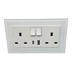 White dual switched electrical outlet with two USB ports on tempered glass panel, mounted on wall.