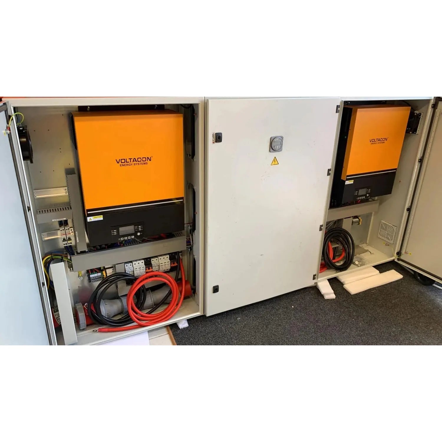 Two open Voltacon energy system cabinets showing orange inverters, black control panels, red cables, and internal electrical 