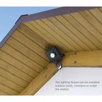 Black LED floodlight with motion sensor mounted on wooden soffit under eave, with text describing outdoor installation option