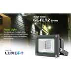 Luxeon GL-FL12 Series LED flood light mounted on wall at night, illuminating brick building facade with warm white light.