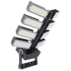 Four-head adjustable LED flood light with white and gray rectangular panels mounted on black articulating arm against white b