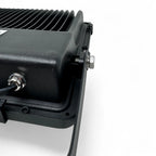 Close-up of black LED floodlight showing finned heat sink, mounting bracket, and cable connector against white background.