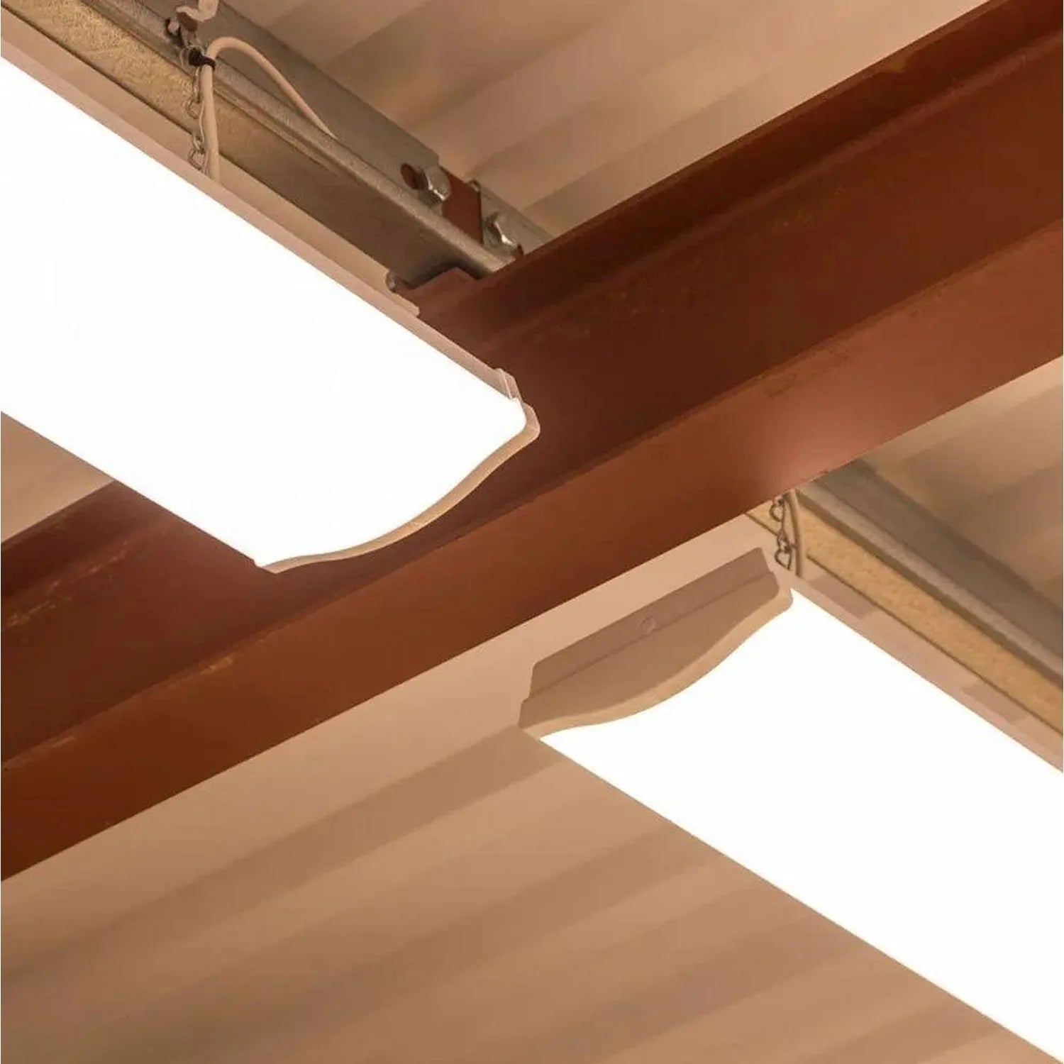 Rectangular LED ceiling light with frosted diffuser mounted flush against beige and brown wooden beams in an installation sho
