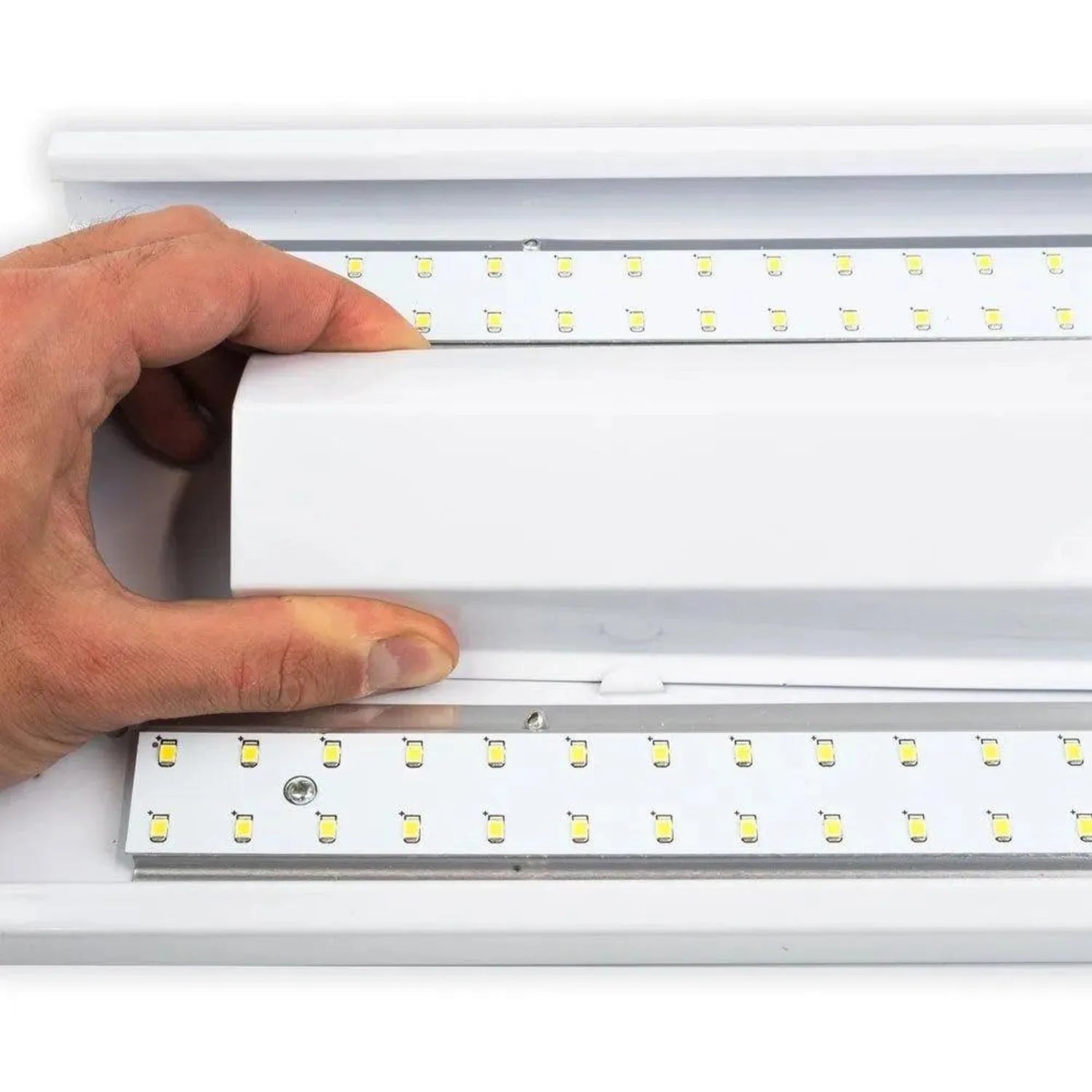 Hand holding edge of white LED ceiling light fixture showing dual rows of yellow LED chips mounted on aluminum rails