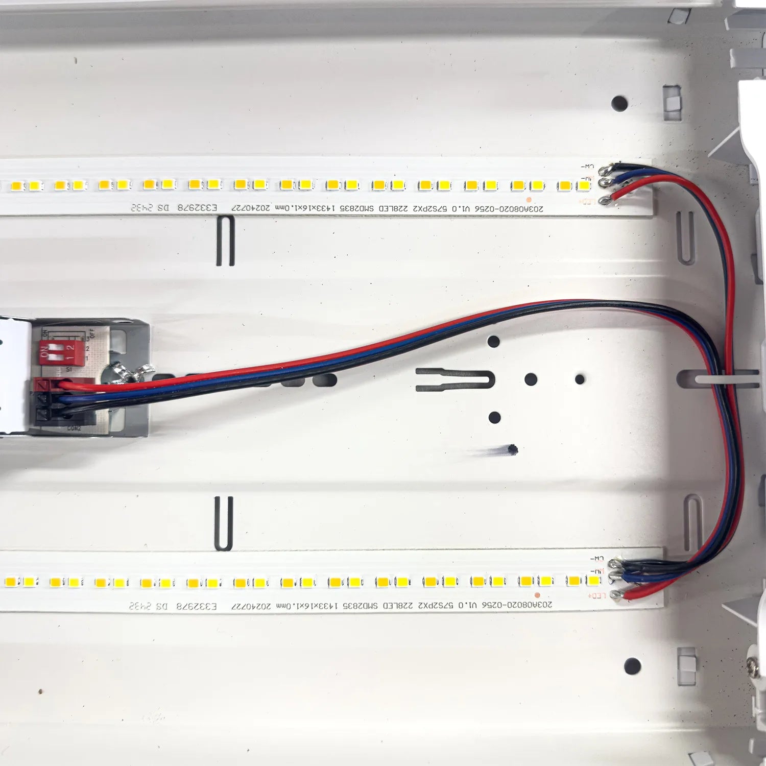 Installation shot of LED ceiling light interior showing dual LED strips with yellow diodes, power supply unit, and red and bl