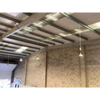 LED high bay light installation in industrial warehouse ceiling with brick walls and metal beam structure.