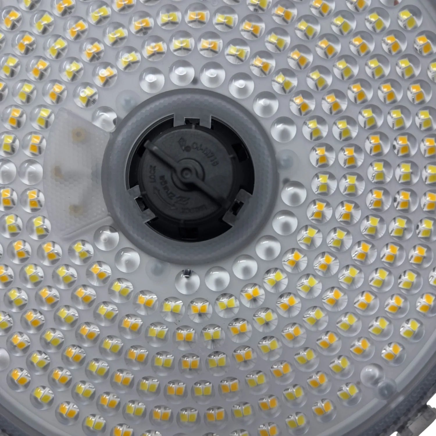 Close-up view of LED high bay light showing dense array of yellow-white LED chips surrounding central black mounting fixture.