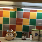 LED under-cabinet lighting installed above colorful tile backsplash in kitchen with utensil holder and containers.