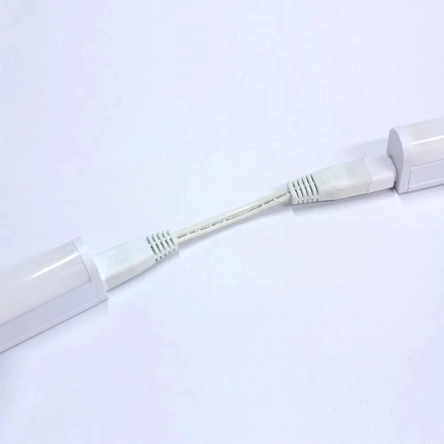 White T5 LED under cabinet tube light with connector cable against light background.