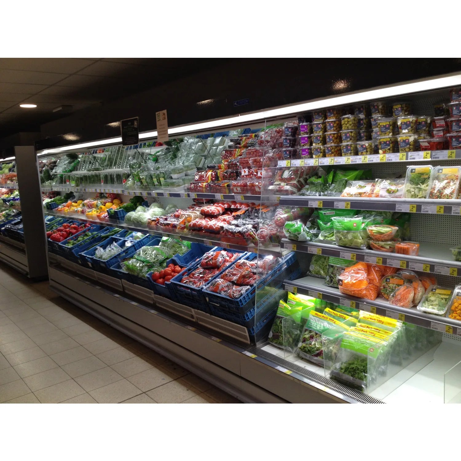 Refrigerated grocery display case with fresh produce, meats, and salads illuminated by bright T5 LED tube lights along the to