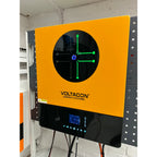 Voltacon Energy Systems inverter mounted on white brick wall, displaying green diagnostic interface on circular black screen 