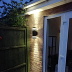 LED outdoor up down wall light mounted on brick wall at night, illuminating entrance doorway.