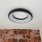 Round black and grey LED ceiling pendant light installed above exposed brick wall, showing modern minimalist design with conc