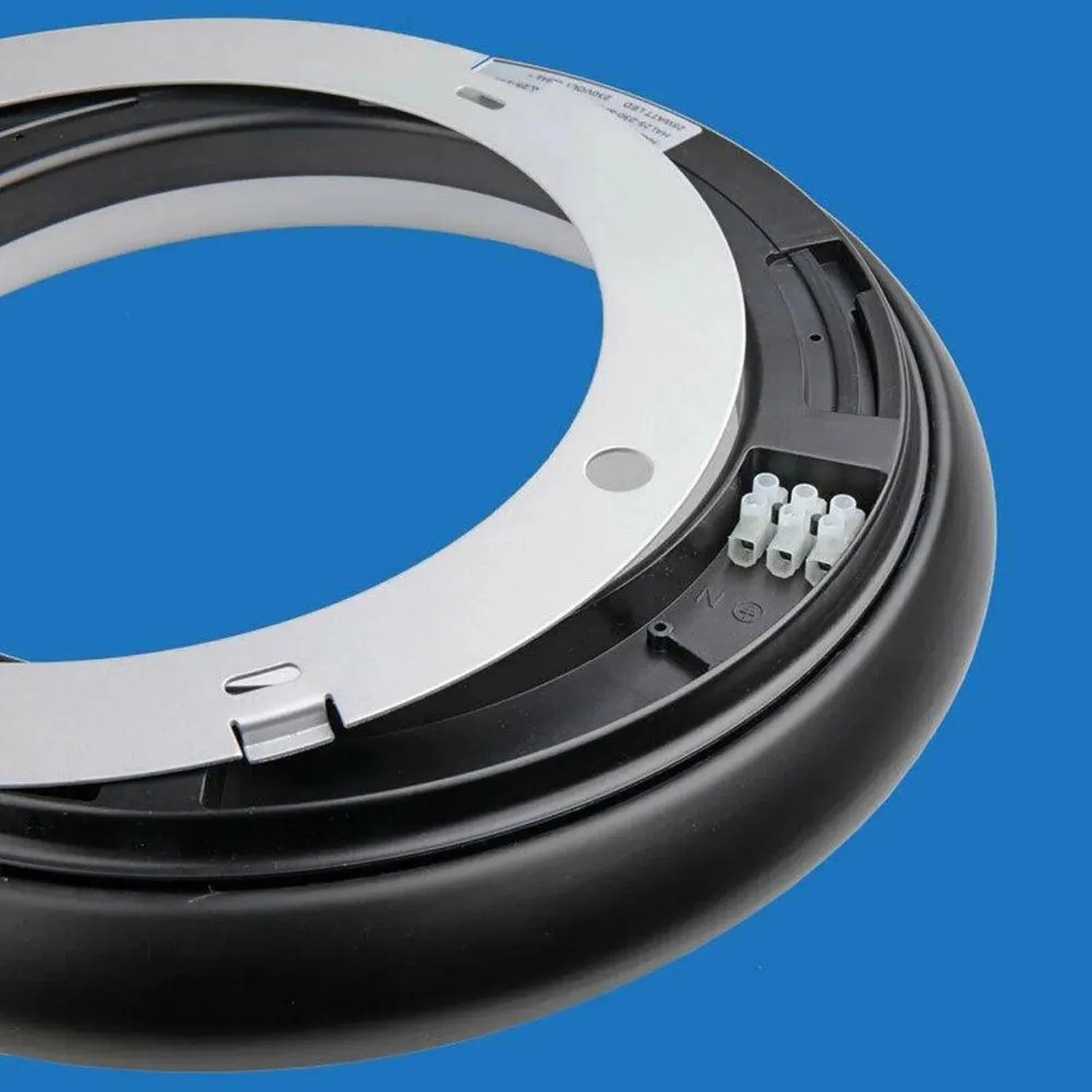 White and black circular LED ceiling light fixture, underside view showing connector pins against blue background.