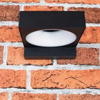 Black rectangular LED wall lamp mounted on red brick wall, white diffuser visible.